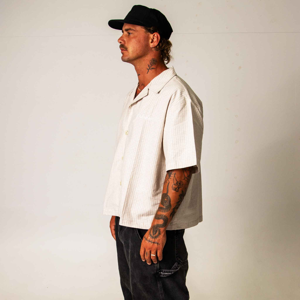 Man wearing a beige shirt and black cap against a plain background