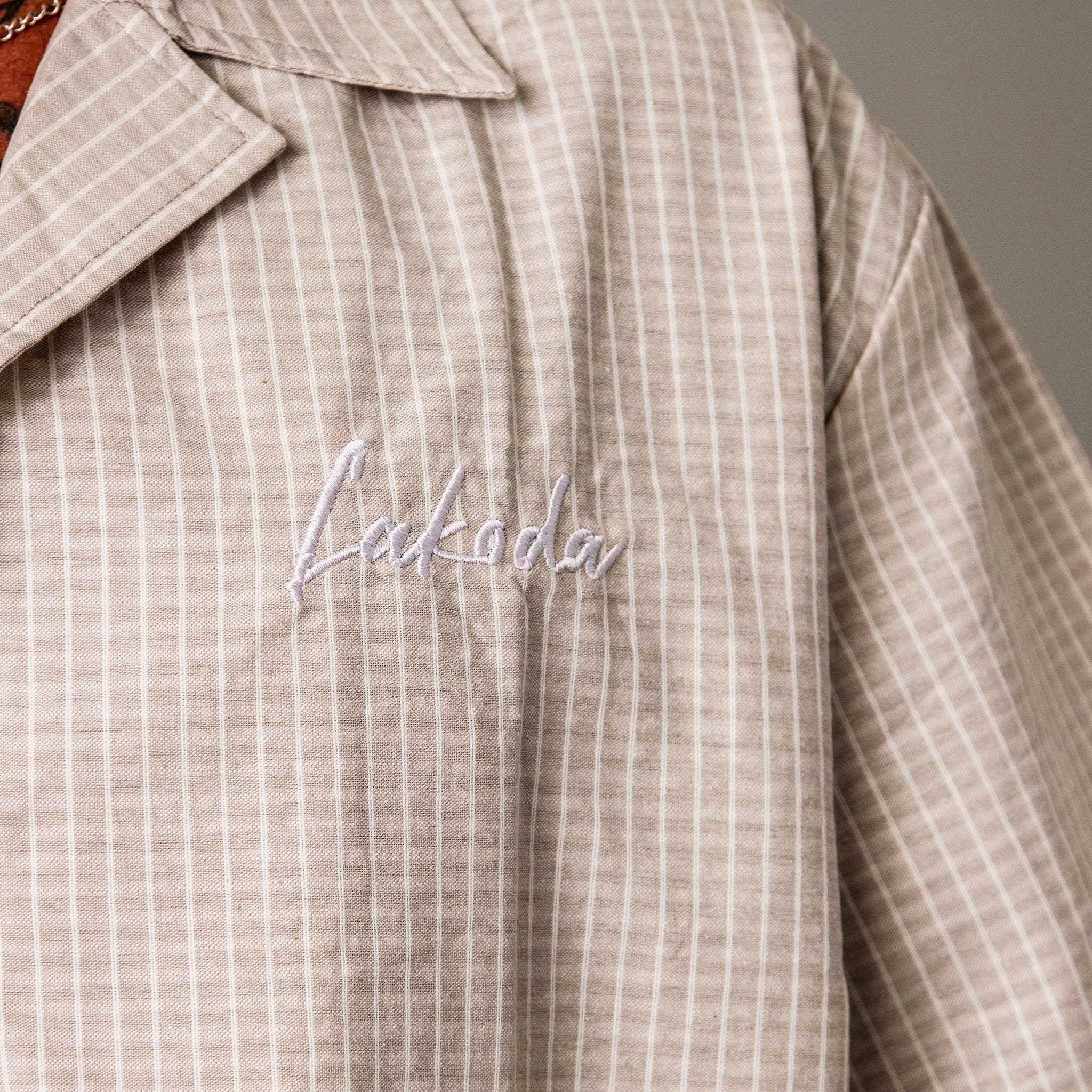 Close-up of a checkered shirt with 'Lakida' embroidery on a neutral background
