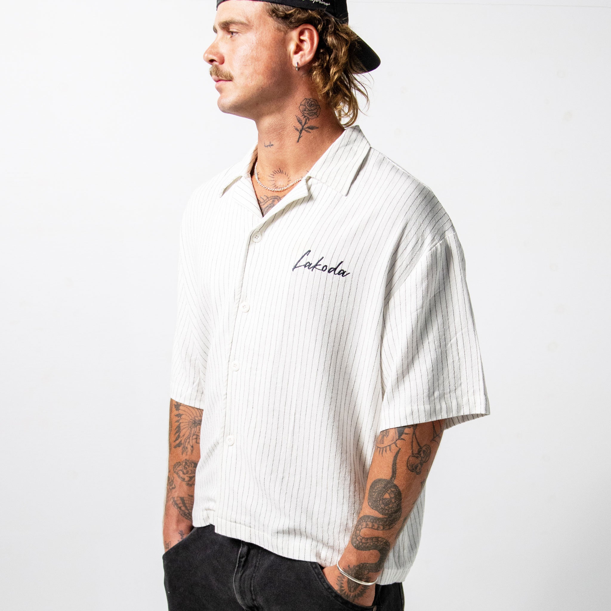 Man wearing a white striped shirt with 'Lakoda' branding on a white background